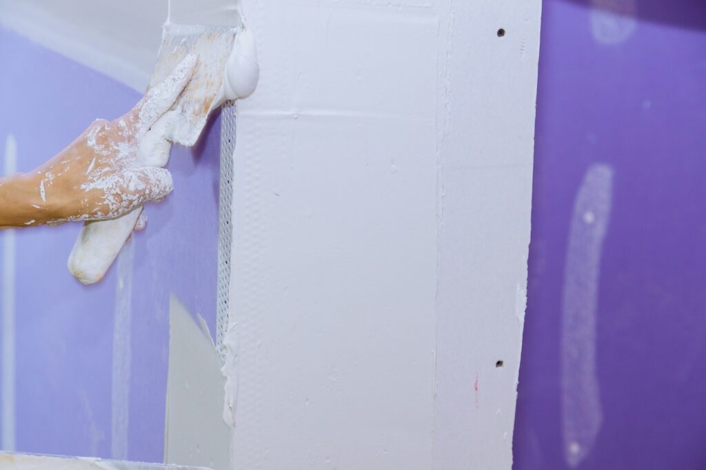 Construction worker plastering the wall, skim coating plaster walls