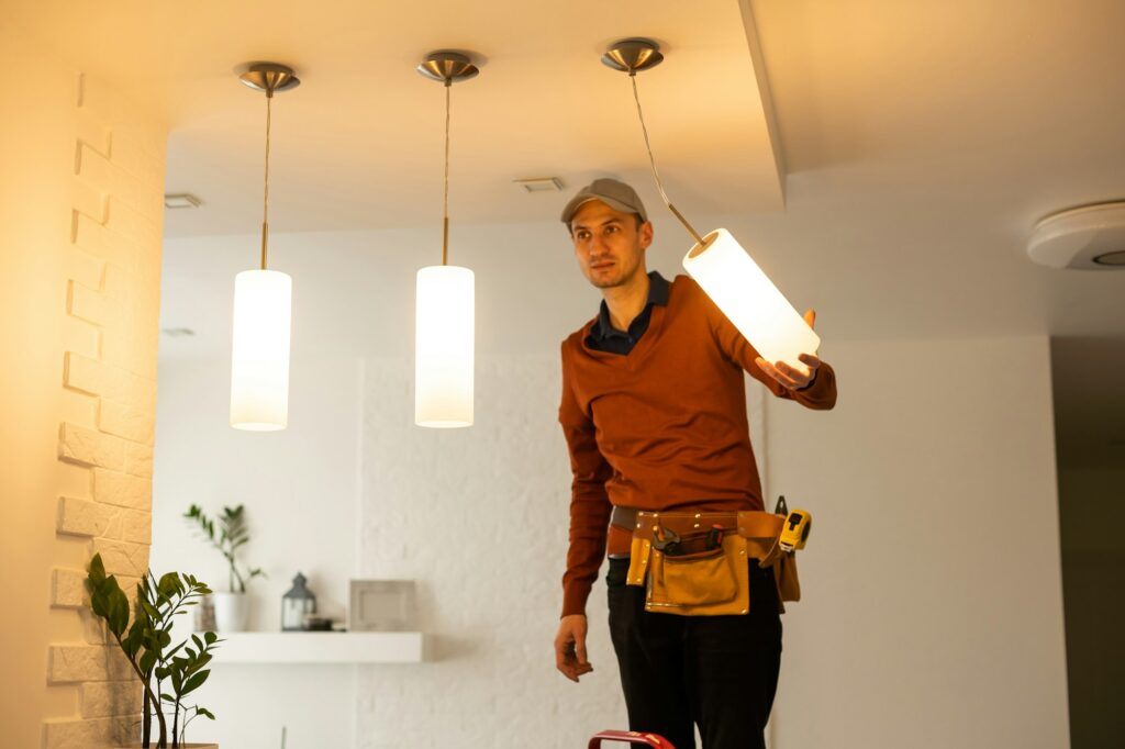 Electrician man working on exterior light, install LED replacement lamp at home. Maintenance concept