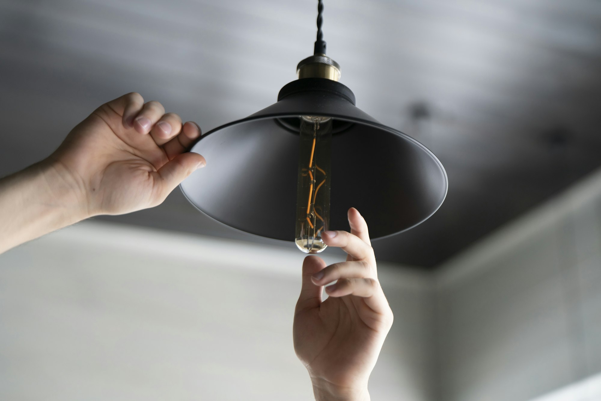 Man Replacing Light Bulb in Ceiling Fixture at Home During Daytime