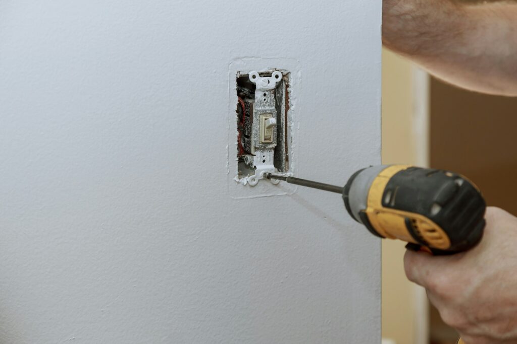 Replacement of the old switch with a new one in closeup of hand of electrician installing wall